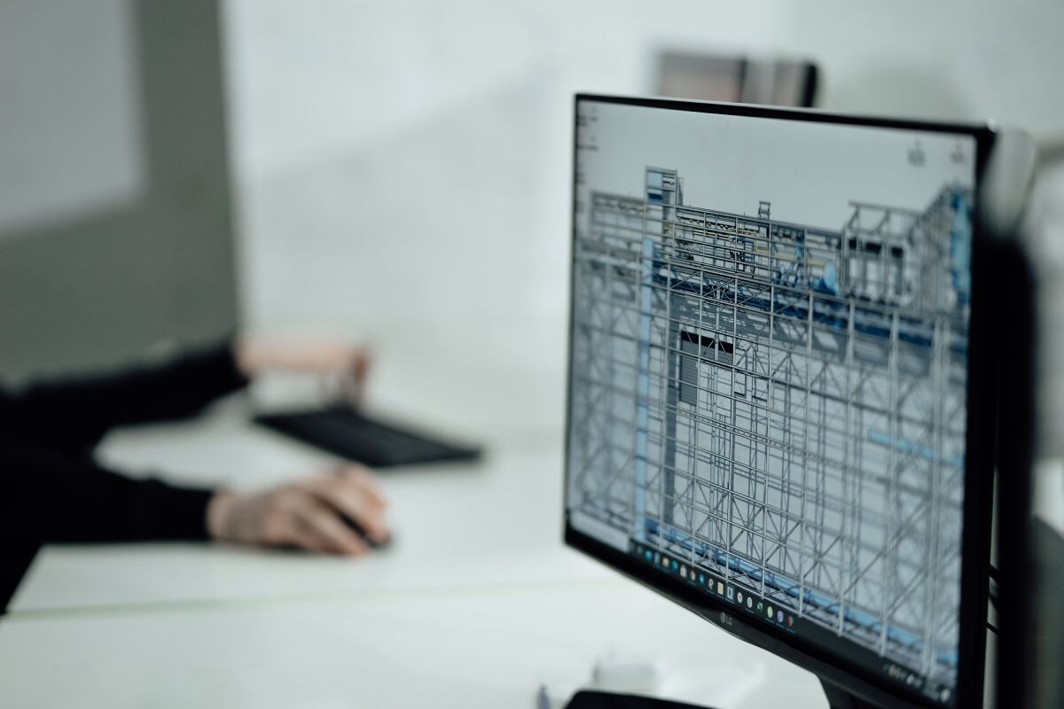 Engineer at a desk reviewing a model on a computer monitor
