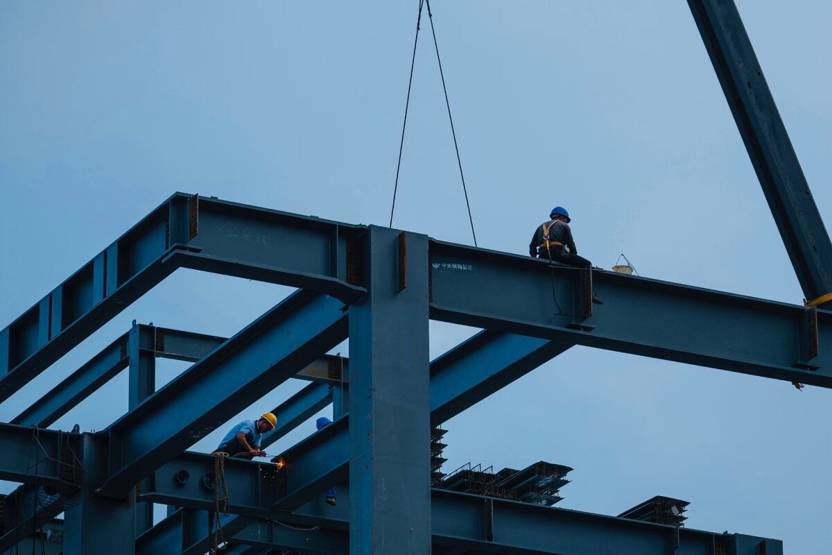 Construction workers assembling a steel structure with a crane